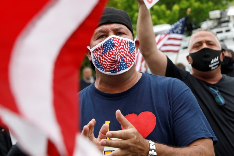 Les partisans de Bobby Catone, propriétaire d'un salon de bronzage Sunbelievable, tiennent des drapeaux et des pancartes après avoir ouvert son entreprise contre les recommandations locales en matière de santé et un ordre de fermeture pendant l'éclosion de la maladie à coronavirus (COVID-19), dans le quartier de Staten Island à New York, États-Unis, 28 mai 2020. REUTERS / Brendan McDermid