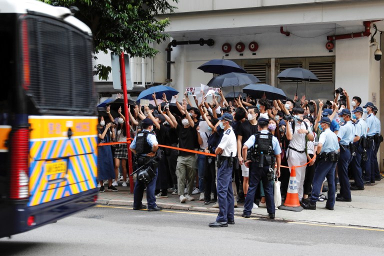 Les partisans lèvent un livre blanc pour éviter les slogans interdits en vertu de la loi sur la sécurité nationale alors qu'ils soutiennent un manifestant anti-droit arrêté, alors qu'un fourgon de prison quitte le tribunal de l'Est à Hong Kong, Chine, le 3 juillet 2020. REUTERS / Tyrone Siu