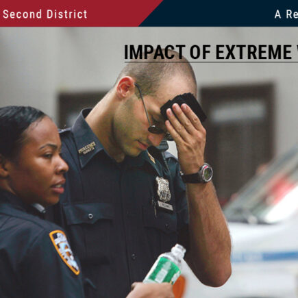 Photo: Two New York City police officers standing on a city street with police vehicle behind them. One is wiping his sweating brow, the other is holding a bottle of water.