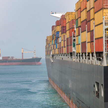 two cargo ships loaded with shipping containers on a calm sea.