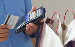 Photo: man holding a wallet in one and a credit card in another with a bag next to him.