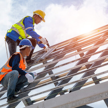 Photo: two construction workers working on a new building wearing hard hats.