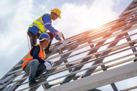 Photo: two construction workers working on a new building wearing hard hats.