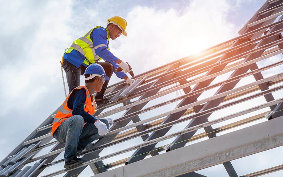 Photo: two construction workers working on a new building wearing hard hats.