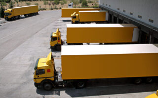 Photo: several yellow trucks backed into a loading dock