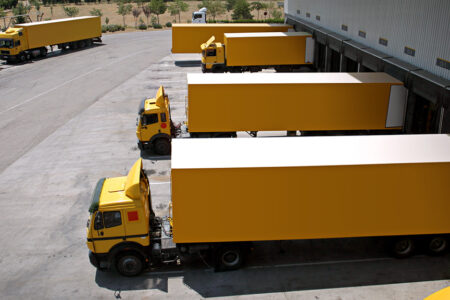 Photo: several yellow trucks backed into a loading dock