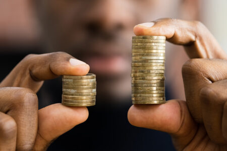 Decorative image: African American Man holding coins in his had showing money disparity.