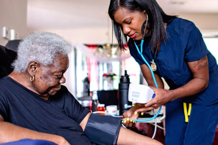 Decorative photo: Nurse taking a women's blood pressure at home.