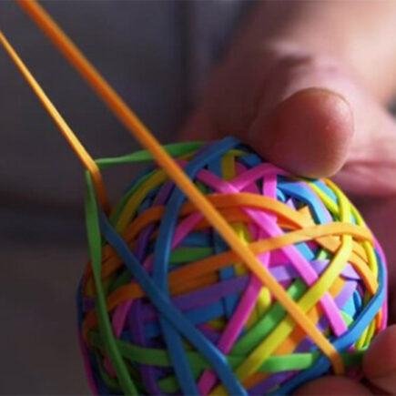 Decorative image: Man pulling an orange rubber band, holding a rubber band ball