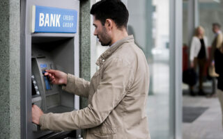 Photo of a caucasian male at Bank ATM machine.