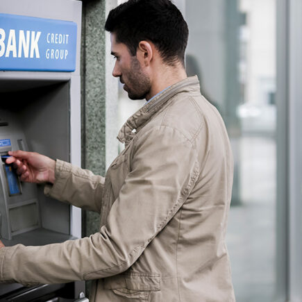 Photo of a caucasian male at Bank ATM machine.
