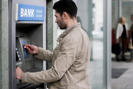Photo of a caucasian male at Bank ATM machine.