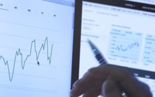 Homme regardant les cours des actions sur un écran d’ordinateur