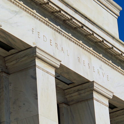 Close up photo of the Federal Reserve building's name carved in the stone at the top of the pillars.