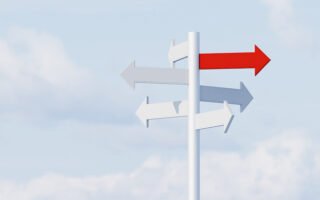 Decorative Photo: Conceptual image of a directional sign with arrow in all directions and one red one standing out from the rest