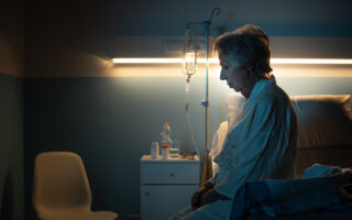 Lonely senior patient suffering from insomnia and sitting on the hospital bed at night