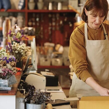 Two Senior owner business shopkeeper wearing aprons checking inventory and packing new orders online for customer eco friendly brown paper wrapped with environmental Sustainability friendly before shipping to customers ,zero waster and plastic free quality control