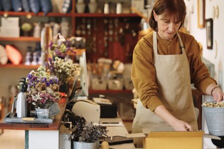 Two Senior owner business shopkeeper wearing aprons checking inventory and packing new orders online for customer eco friendly brown paper wrapped with environmental Sustainability friendly before shipping to customers ,zero waster and plastic free quality control