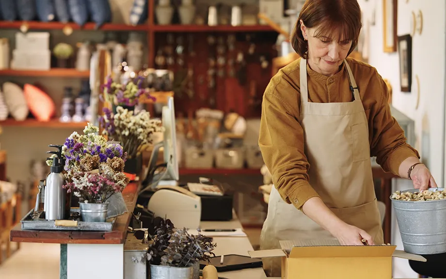 Two Senior owner business shopkeeper wearing aprons checking inventory and packing new orders online for customer eco friendly brown paper wrapped with environmental Sustainability friendly before shipping to customers ,zero waster and plastic free quality control