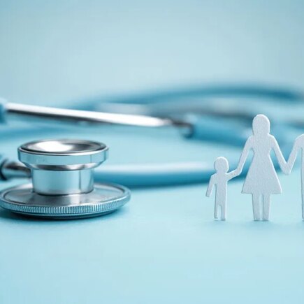 Photo: light blue background, with a stethoscope and white paper image of family standing up.