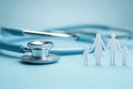 Photo: light blue background, with a stethoscope and white paper image of family standing up.