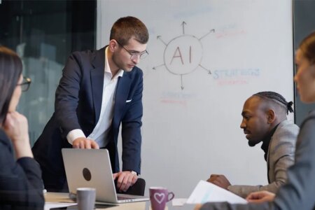 Image of workers in business suits being trained in AI through whiteboard and computer screen