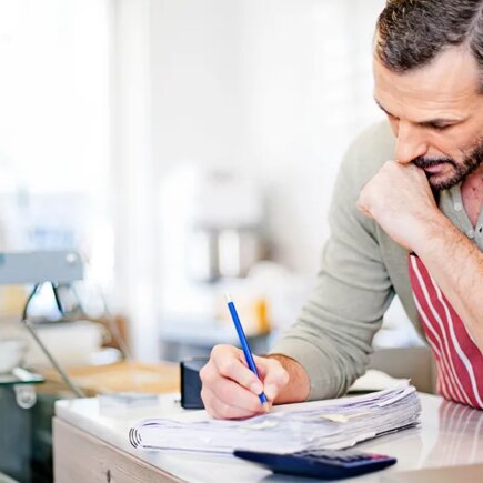 Small Business owner calculating at the counter of his cafe.