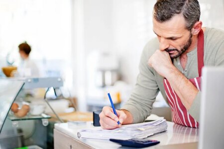 Small Business owner calculating at the counter of his cafe.