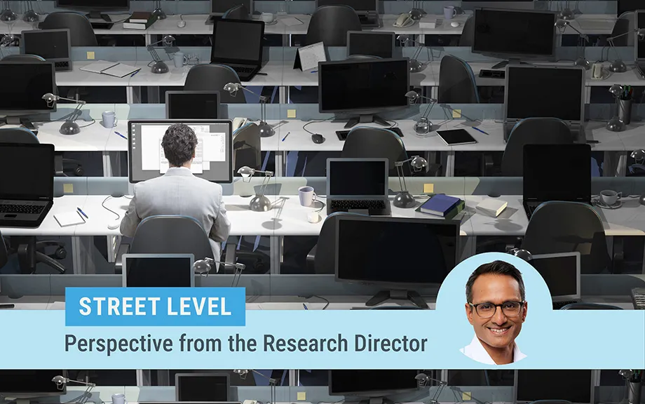Street level column by Research Director Kartik Athreya. Image of Athreya on top of a photo of a large room with rows of desks and laptops with only one man sitting at one desk working.