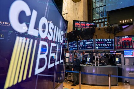 Floor of the stock exchange with a large screen in front that says closing bell.