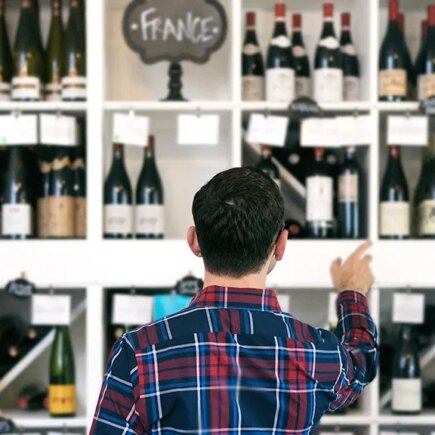 Owner/salesperson and customers inside a small, local wine shop.