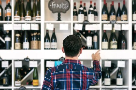 Owner/salesperson and customers inside a small, local wine shop.